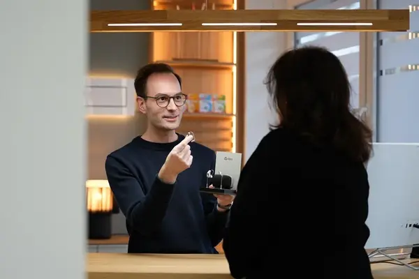 Ein Hörgeräteakustiker berät eine Kundin persönlich zu modernen Hörgeräten am Tresen.